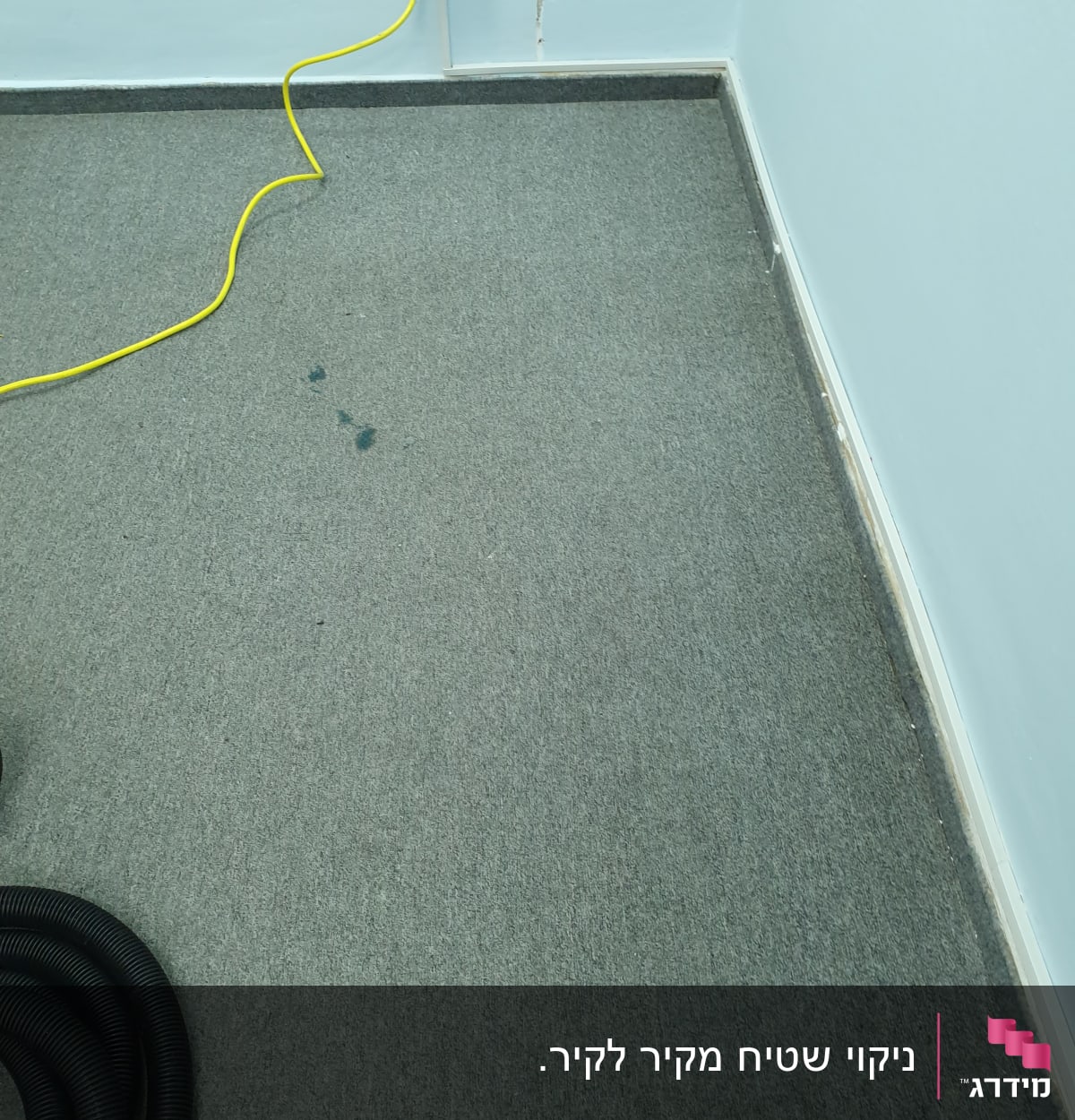 שטיח אפור עם כתמים, כבל חשמל צהוב ושואב אבק